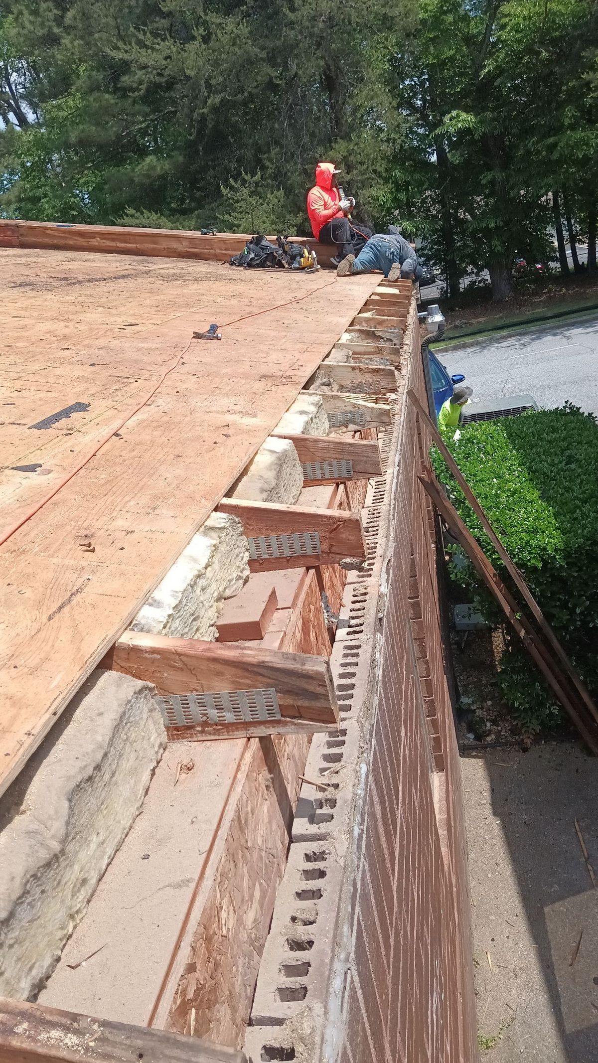 Aerial view of commercial roof replacement mid-installation — crew working on metal panel system